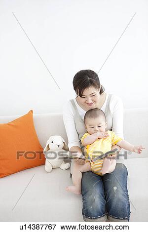 Stock Photo - Mother reading a book to her baby. Fotosearch