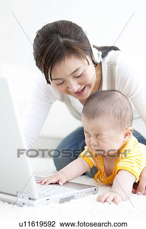 Mother showing her baby a laptop View Large Photo Image Stock Image - Mother showing her baby a laptop. Fotosearch