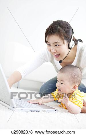 Stock Photo - Mother showing her baby a laptop. Fotosearch