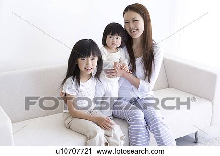 Stock Image - Mother sitting with her two daughters. Fotosearch