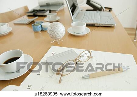 Stock Photography - Office with on diary, glasses and coffee cup on desk. Fotosearch