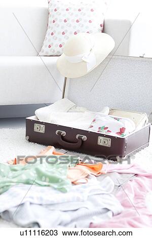 Stock Image - Open suitcase on living room floor. Fotosearch