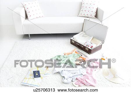 Stock Image - Open suitcase on living room floor. Fotosearch