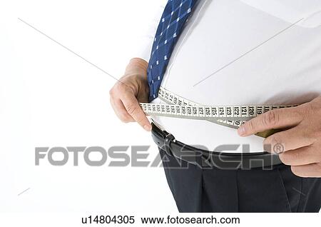 Overweight businessman measuring his pot belly View Large Photo Image Stock Photography - Overweight businessman measuring his pot belly. Fotosearch