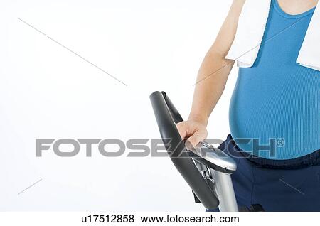 Stock Photo - Overweight man exercising on a gym machine. Fotosearch