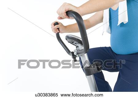Stock Photography - Overweight man exercising on a gym machine. Fotosearch