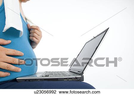 Stock Image - Overweight man in gym gear using a laptop. Fotosearch