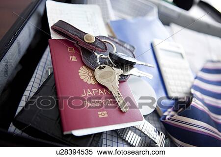 Stock Photography - Passport and keys on top of a packed suitcase. Fotosearch