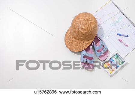 Stock Photograph - Pastel crayons with drawing on a note pad, a summer hat and sandals. Fotosearch