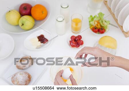 Picture - Person breaking eggs into bowl. Fotosearch