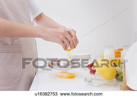 Stock Image - Person breaking eggs into bowl. Fotosearch