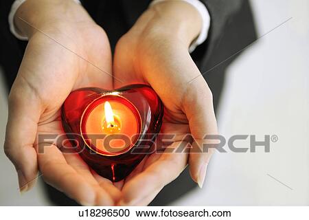 Stock Image - Person holding heart shaped candle. Fotosearch