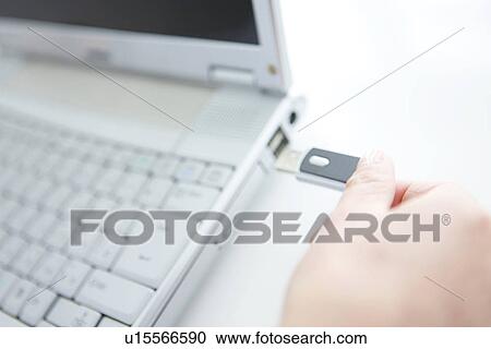 Stock Image - Person inserting USB stick into laptop. Fotosearch
