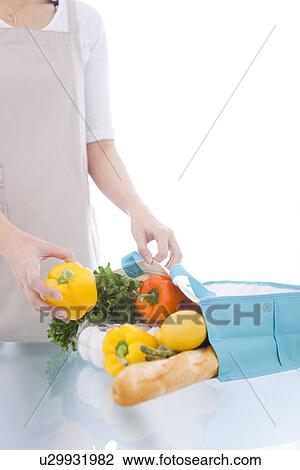 Stock Image - Person unpacking groceries from eco-bag. Fotosearch