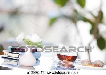 Stock Image - Plate of cookies and a cup of tea on a table with a cellphone and diary. Fotosearch