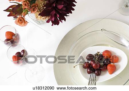 Stock Image - Plate of fruit and vase of flowers. Fotosearch