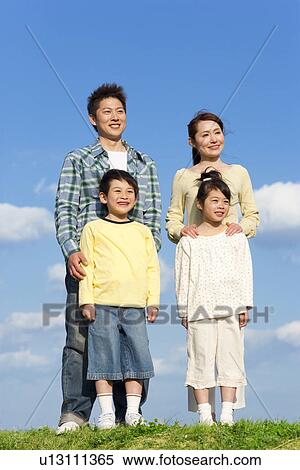 Stock Photography - Portrait of a family of four at the park against a blue sky. Fotosearch