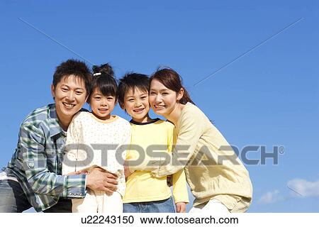 Portrait of a family of four hugging against a blue sky View Large Photo Image Stock Image - Portrait of a family of four hugging against a blue sky. Fotosearch