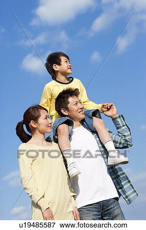 Stock Photo - Portrait of a family with young son against a blue sky. Fotosearch