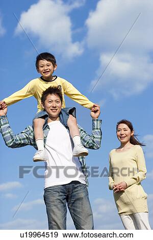 Stock Photo - Portrait of a family with young son playing against a blue sky. Fotosearch