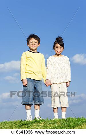 Stock Photograph - Portrait of brother and sister against a blue sky. Fotosearch