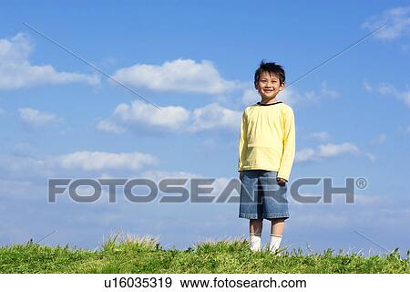 Stock Photo - Portrait of young boy at the park against a blue sky. Fotosearch