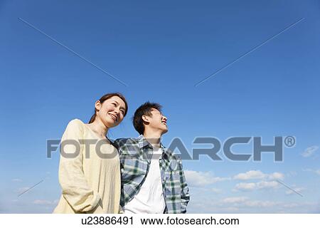 Stock Image - Portrait of young couple against a blue sky. Fotosearch