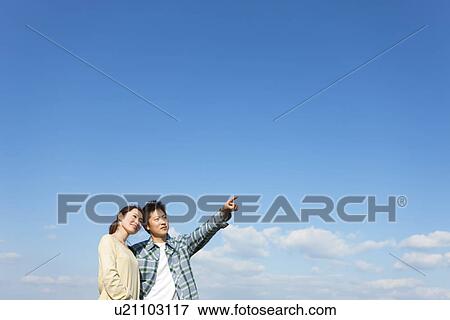 Portrait of young couple looking into the distance against a blue sky View Large Photo Image Stock Photo - Portrait of young couple looking into the distance against a blue sky. Fotosearch