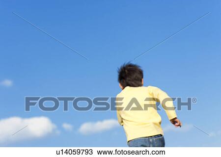 Rear view of young boy running against a blue sky View Large Photo Image Stock Image - Rear view of young boy running against a blue sky. Fotosearch