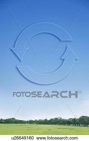 Stock Image - Recycling symbol in blue sky over field and trees. Fotosearch
