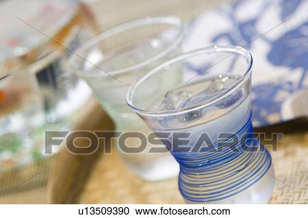 Saki cups on a tray next to a Japanese fan with a fishbowl in the background View Large Photo Image Stock Image - Saki cups on a tray next to a Japanese fan with a fishbowl in the background. Fotosearch