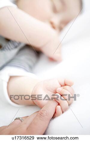 Stock Photo - Sleeping baby holding his mother's finger. Fotosearch