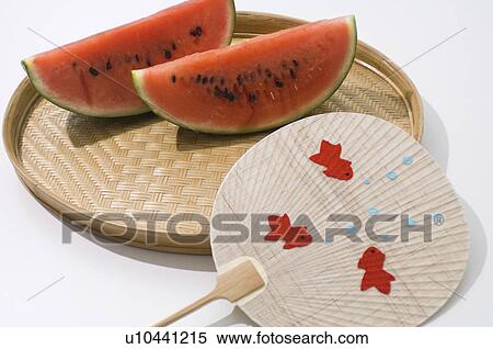 Slices of watermelon on a tray next to a goldfish patterned fan View Large Photo Image Stock Photography - Slices of watermelon on a tray next to a goldfish patterned fan. Fotosearch