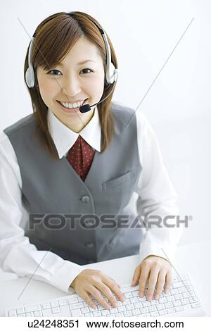 Smiling businesswoman wearing headset and typing on computer View Large Photo Image Stock Image - Smiling businesswoman wearing headset and typing on computer. Fotosearch