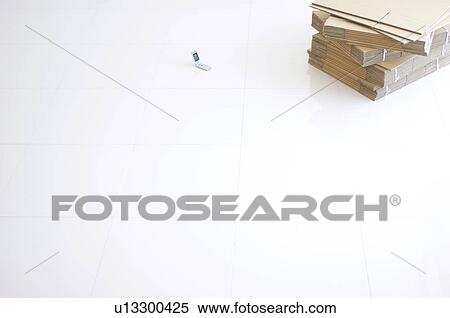 Stock Photography - Stack of flattened cardboard boxes and a mobile phone on the floor. Fotosearch