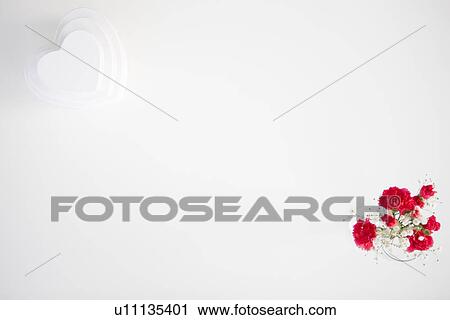Stock Image - Stack of heart shaped gift boxes and a vase of carnations and baby's breath. Fotosearch