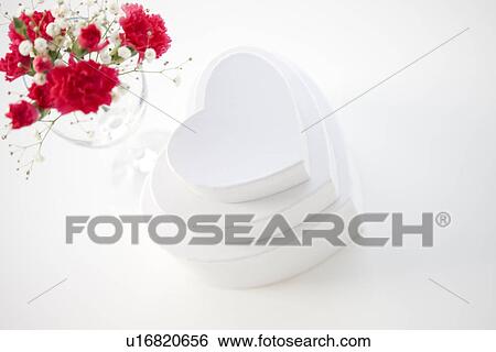 Stock Photograph - Stack of heart shaped gift boxes and a vase of carnations and baby's breath. Fotosearch