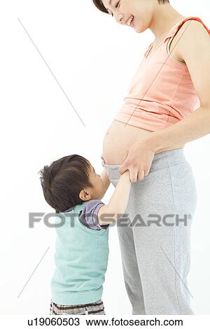 Studio portrait of pregnant woman and her preschool age son touching her belly View Large Photo Image Stock Image - Studio portrait of pregnant woman and her preschool age son touching her belly. Fotosearch
