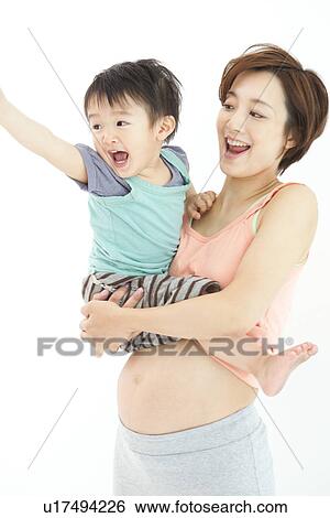 Stock Photograph - Studio portrait of pregnant woman hugging her preschool age son. Fotosearch