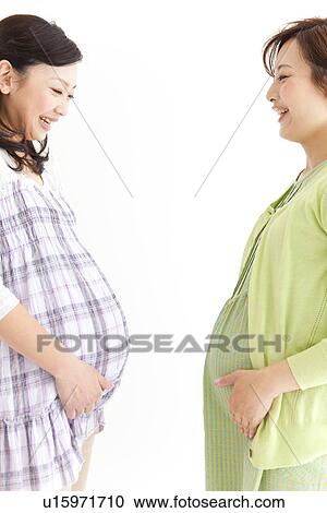 Studio portrait of two pregnant women standing facing each other View Large Photo Image Stock Image - Studio portrait of two pregnant women standing facing each other. Fotosearch