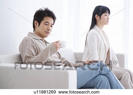 Sullen looking young couple sitting on couch View Large Photo Image Stock Photo - Sullen looking young couple sitting on couch. Fotosearch