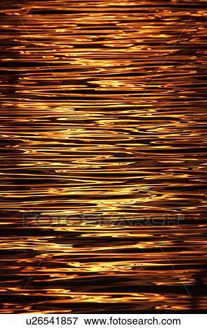 Stock Photo - Sunset reflecting off rippled water surface. Fotosearch
