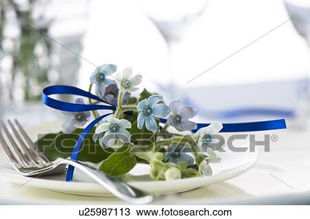 Stock Image - Table setting with flowers and blue ribbon. Fotosearch