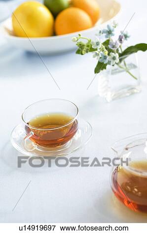 Stock Photo - Tea cup with bouquet and bowl of citrus fruit. Fotosearch