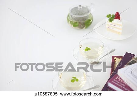 Stock Photography - Two cups of herbal tea and a piece of cake. Fotosearch