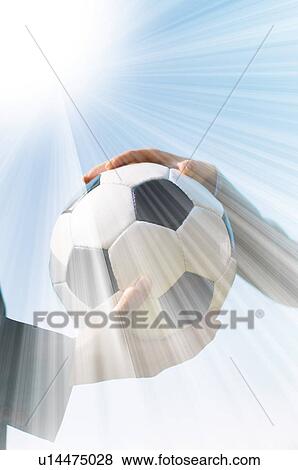 Stock Photo - Two people holding a soccer ball under a bright sun. Fotosearch