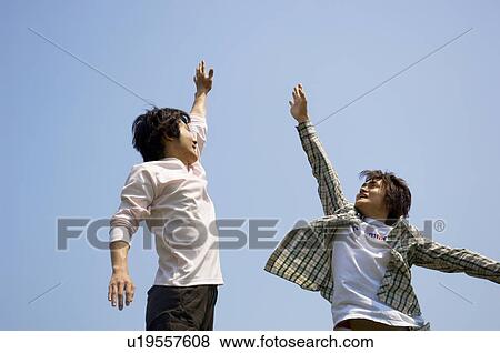Two young men doing a high five View Large Photo Image Stock Photo - Two young men doing a high five. Fotosearch