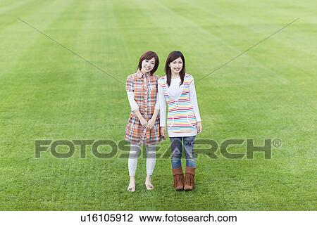Stock Image - Two young women standing on sports field. Fotosearch