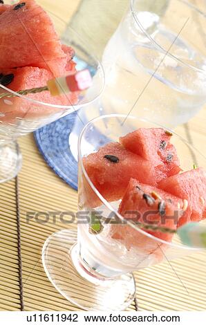 Stock Image - Watermelon in dishes and a glass of water. Fotosearch