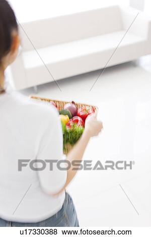Stock Photo - Woman carrying basket with fresh vegetables. Fotosearch
